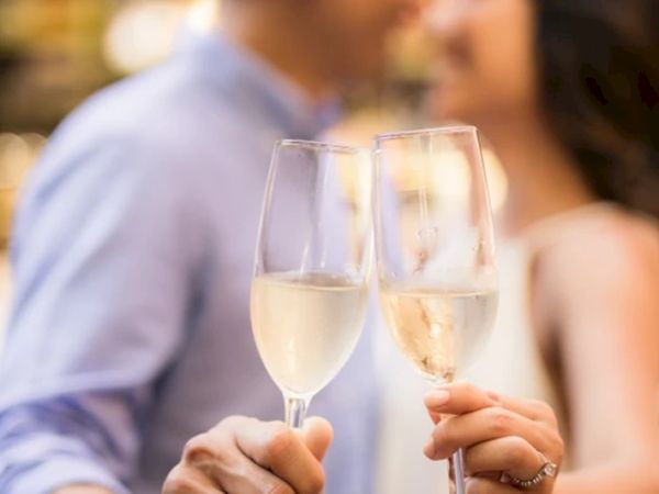 Two people clinking glasses of champagne in a toast, likely celebrating an occasion, with a blurred background creating an intimate atmosphere.