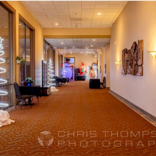 A well-lit hallway with red carpet, modern decor, and white spiral Christmas decorations. Photo credit to Chris Thompson Photography.